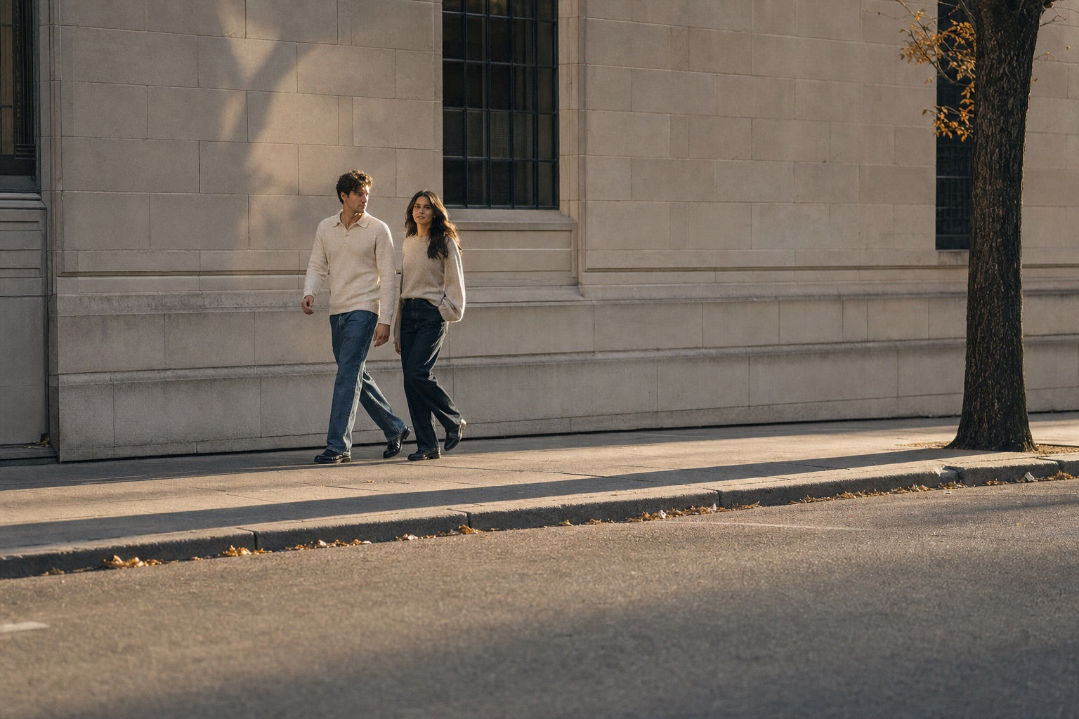 Two people walking down a city street wearing knitwear and jeans